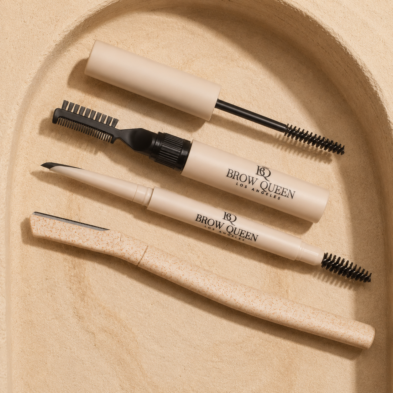 Brow grooming products including a brow pencil and brow brush on a beige background.