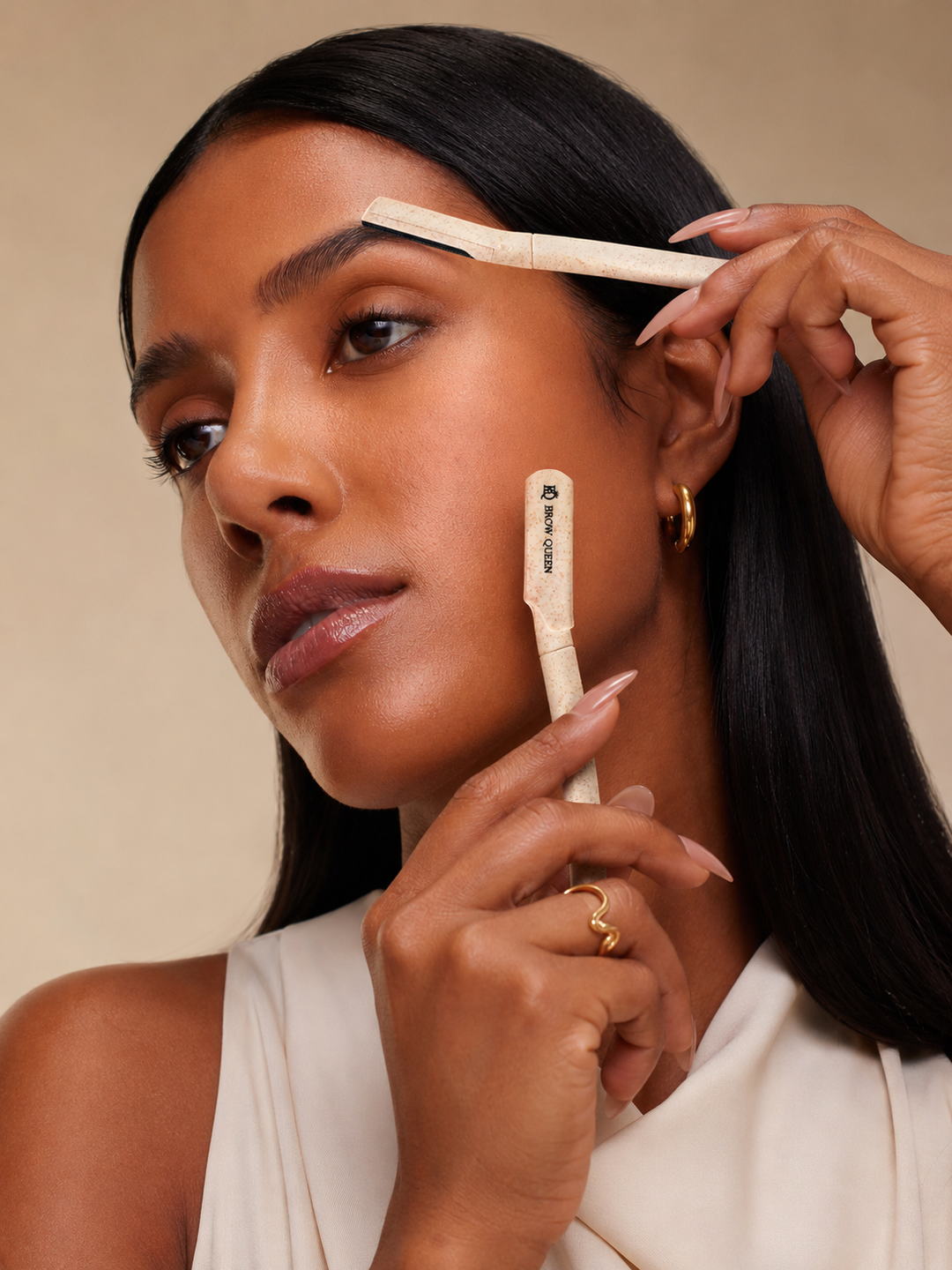 Woman using a brow shape on her eyebrows with a neutral background
