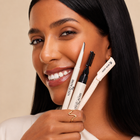 Woman holding Brow Queen eyebrow grooming tools with a neutral background