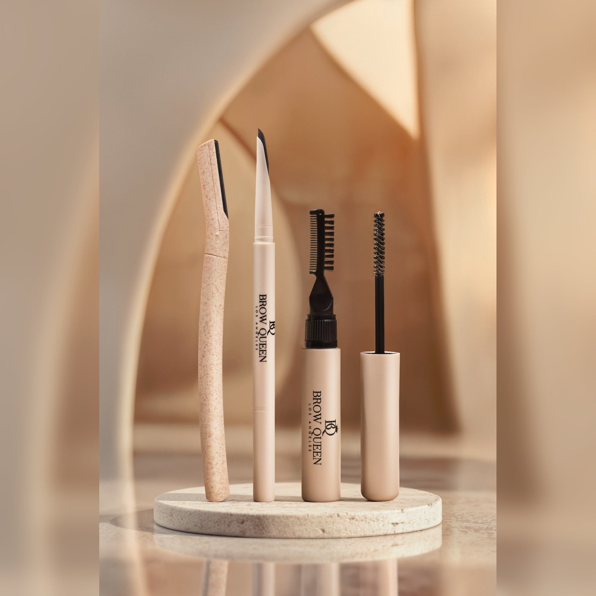 Set of brow grooming tools on a round stone platform with a blurred background