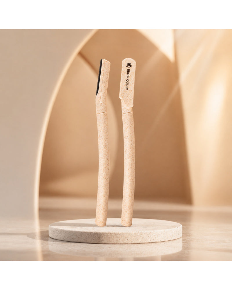 Two dermaplaning tools standing upright on a round stand against a warm neutral background.
